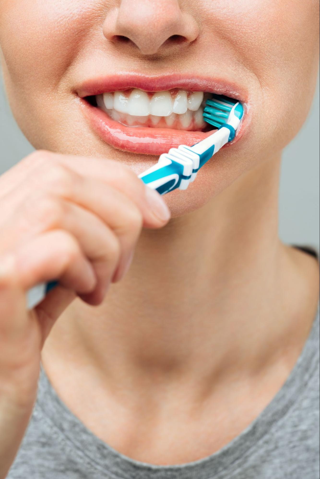 woman brushing her teeth with a toothbrush