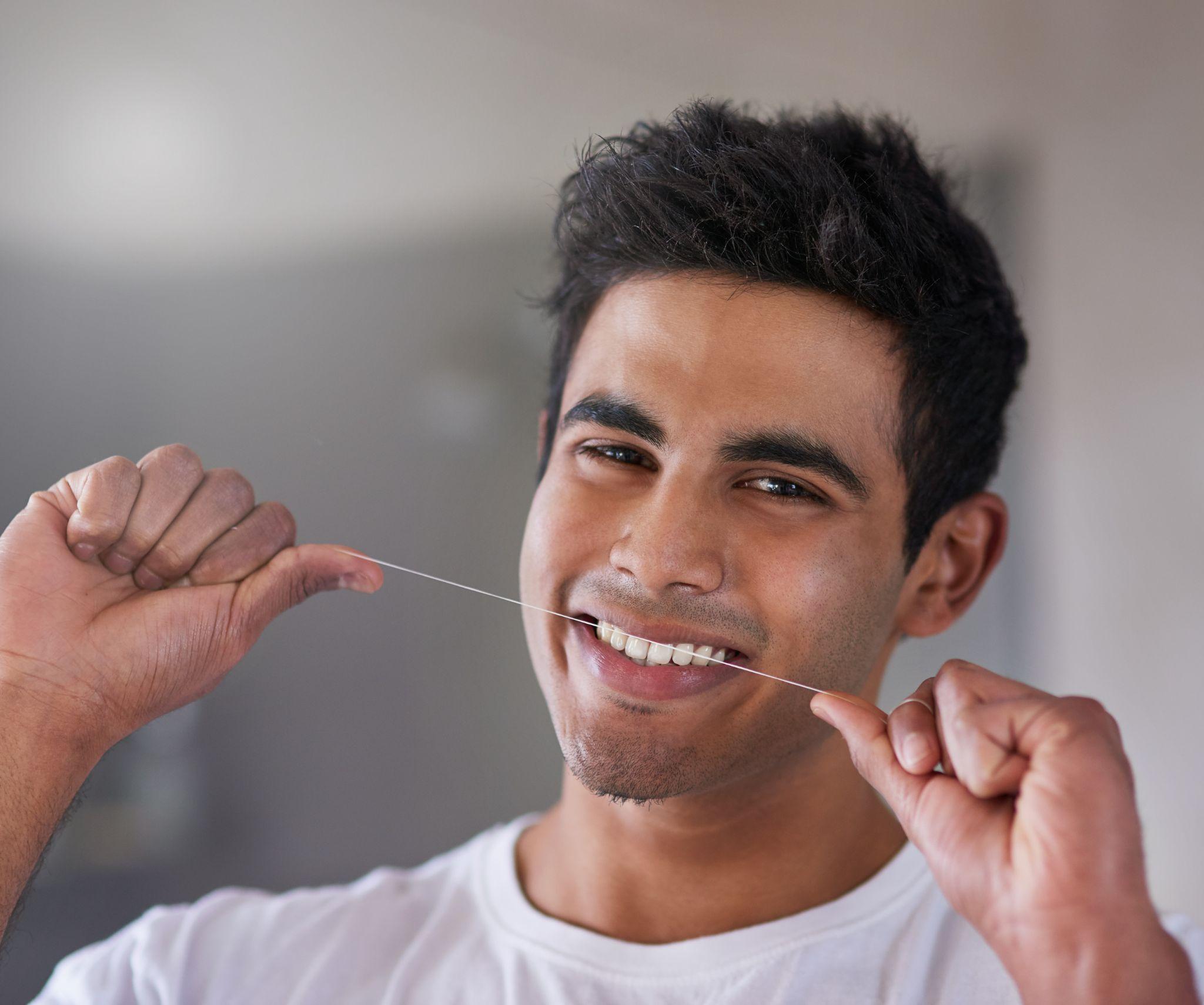 keeping it clean in the spaces in between portrait of a happy young man flossing his teeth at home