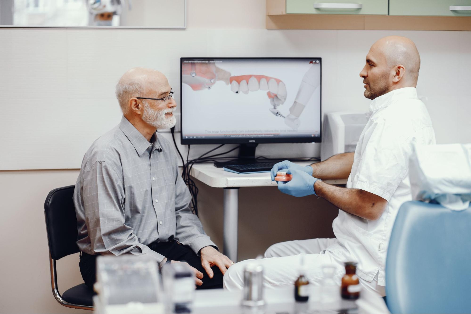 man sitting with patient whilst showing him a youtube video