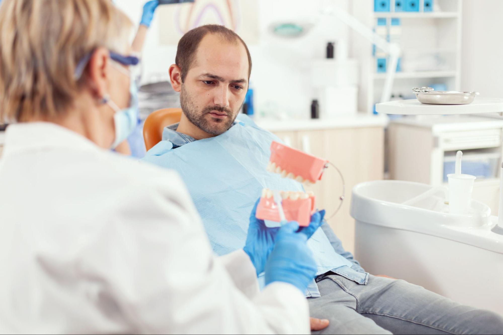 dentist showing dental prop to patient